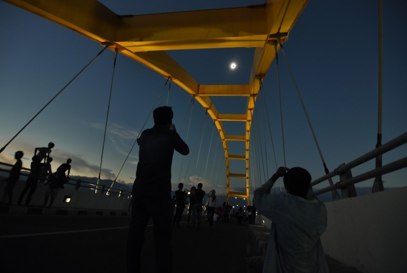 Warga menyaksikan fase puncak Gerhana Matahari Total (GMT) yang dilihat dari Jembatan Teluk Palu, Sulawesi Tengah, Rabu (9/3).
