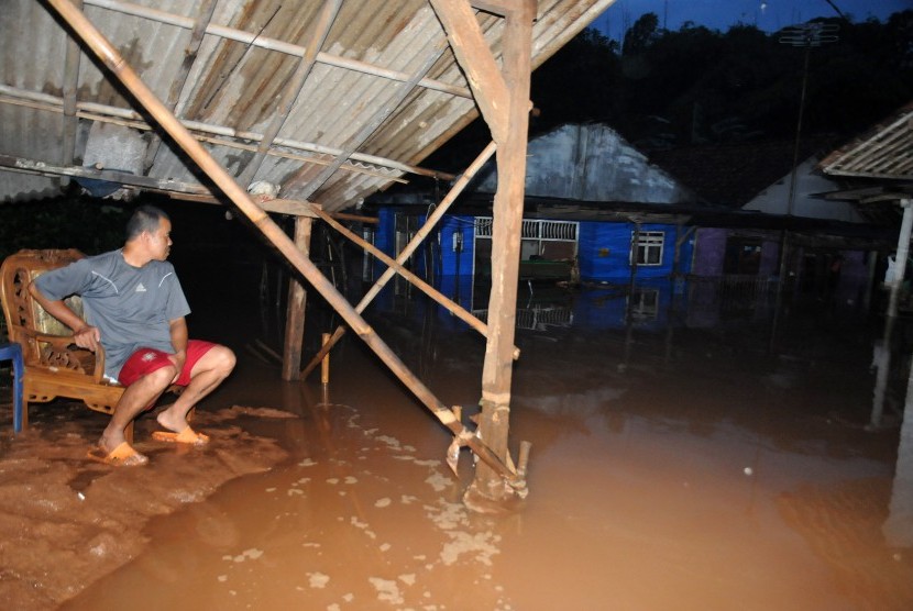 Warga menyaksikan kondisi rumah yang terendam banjir akibat meluapnya Kali Cikumpa di Jalan Raya KSU, Depok, Jawa Barat, Jumat (11/3).
