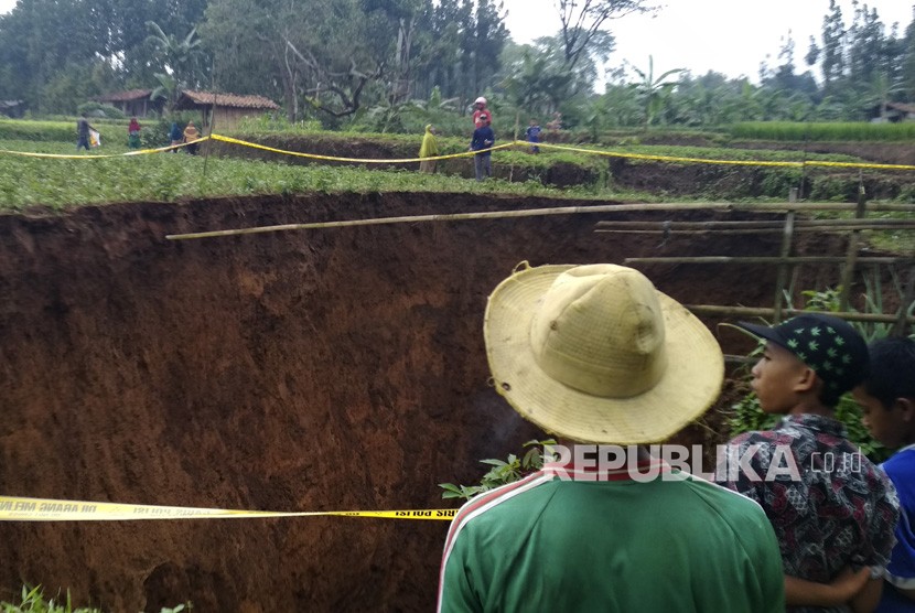Warga menyaksikan lubang raksasa di area persawahan di Desa Sukamaju, Kadudampit, Kabupaten Sukabumi, Jawa Barat, Ahad (28/4/2019).