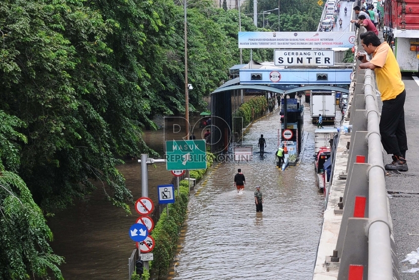 Warga menyaksikan pintu tol terendam banjir , Sunter, Jakarta, Selasa (10/2). (Republika/ Tahta Aidilla)