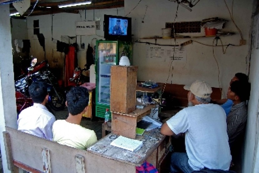  Warga menyaksikan televisi yang menyiarkan hasil rekapitulasi oleh KPU di sebuah tempat cuci motor Jalan Jati Murni, Jakarta Selatan, Selasa (22/7). Warga antusias menunggu hasil rekapitulasi KPU terkait calon presiden dan calon wakil presiden.