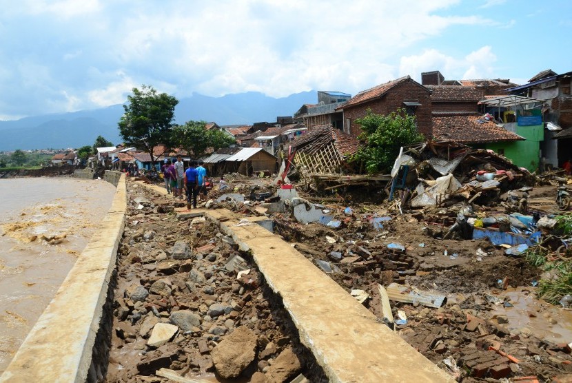 Warga menyaksikkan sisa puing bangunan rumah yang roboh akibat diterjang banjir bandang aliran Sungai Ciamanuk di Kampung Cimacan, Kecamatan Tarogong, Kabupaten Garut, Jawa Barat, Rabu (21/9). 