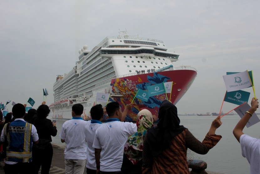 Warga menyambut kedatangan kapal pesiar Genting Dream yang akan sandar di Dermaga Jamrud Utara, Pelabuhan Tanjung Perak Surabaya, Jawa Timur, Selasa (12/12). Kapal pesiar tersebut mengangkut sekitar 2.561 wisatawan asing yang berkunjung ke sejumlah tempat wisata di Kota Surabaya.