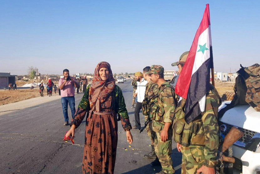 Warga menyambut tentara Suriah setelah mereka tiba di Kota Tal Tamr dekat perbatasan Turki, Senin (14/10).