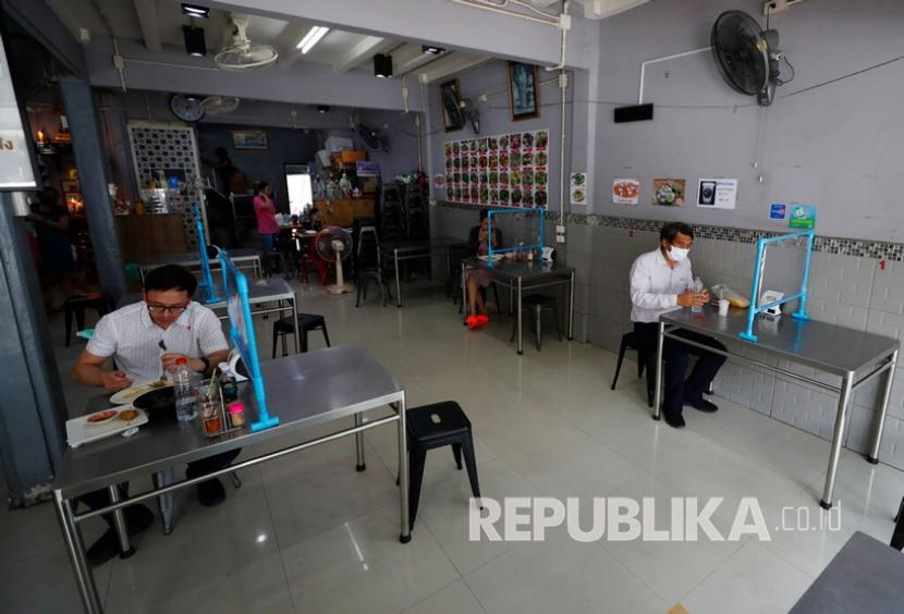 Warga menyantap makan siang di balik tirai plastik untuk membantu menekan penyebaran virus corona di Bangkok, Thailand, Selasa (5/5). Pemerintah Thailand melonggarkan pembatasan pada hari Minggu 3 Mei 2020 setelah diberlakukan minggu lalu untuk memerangi penyebaran COVID-19. 