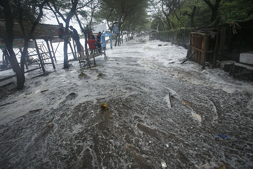 Warga menyeberang genangan banjir rob di kawasan pantai Somandeng, Gunungkidul, DI Yogyakarta, Kamis (9/6).