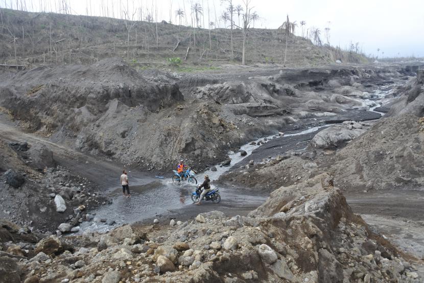 Warga menyeberang melewati aliran sungai yang menjadi lokasi turunnya material vulkanis Gunung Semeru di Dusun Curah Kobokan, Desa Supiturang, Pronojiwo, Lumajang, Jawa Timur, Minggu (9/1/2022). Pusat Vulkanologi dan Mitigasi Bencana Geologi (PVMBG) mengimbau warga mewaspadai dampak aktivitas vulkanik Gunung Semeru di wilayah Provinsi Jawa Timur.