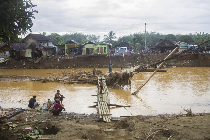 Warga menyeberang sungai menggunakan jembatan darurat akibat jembatan gantung di Desa Alat putus akibat banjir bandang di Kabupaten Hulu Sungai Tengah, Kalimantan Selatan, Rabu (20/1/2021). Berdasarkan data Badan Penanggulangan Bencana Daerah (BPBD) Provinsi Kalimantan Selatan pada Rabu (20/1/2021) sebanyak 21 Jembatan, 110 tempat ibadah, 76 sekolah serta 18.294 meter jalan terdampak banjir dan longsor di Kalimantan Selatan.