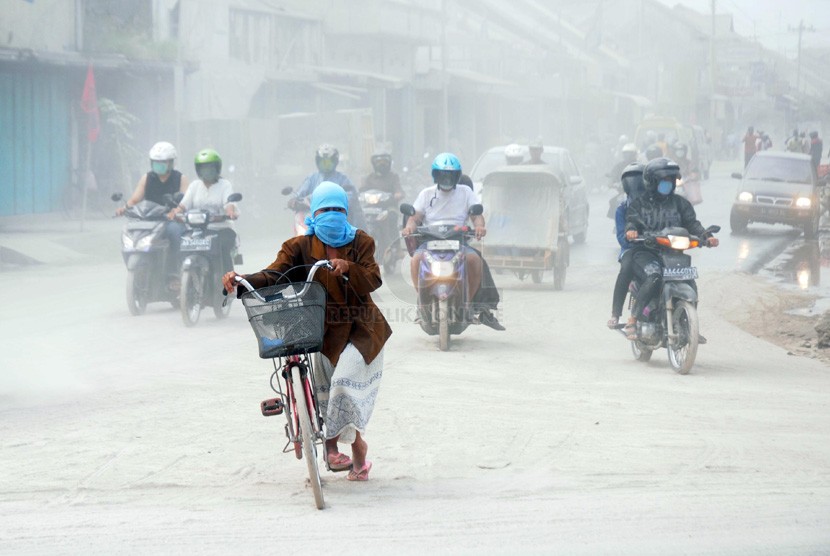  Warga menyeberangi jalan yang tertutup abu vulkanik di kawasan Kutoarjo, Purworejo, Jawa Tengah, Sabtu (15/2). (Republika/Adhi Wicaksono)