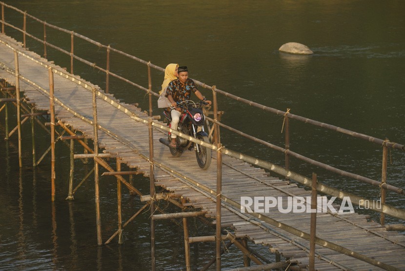 Warga melewati jembatan bambu di Kulon Progo. Ketua I DPRD Kabupaten Kulon Progo mendesak agar pemerintah membangun infrastruktur di Sentolo. Ilustrasi.