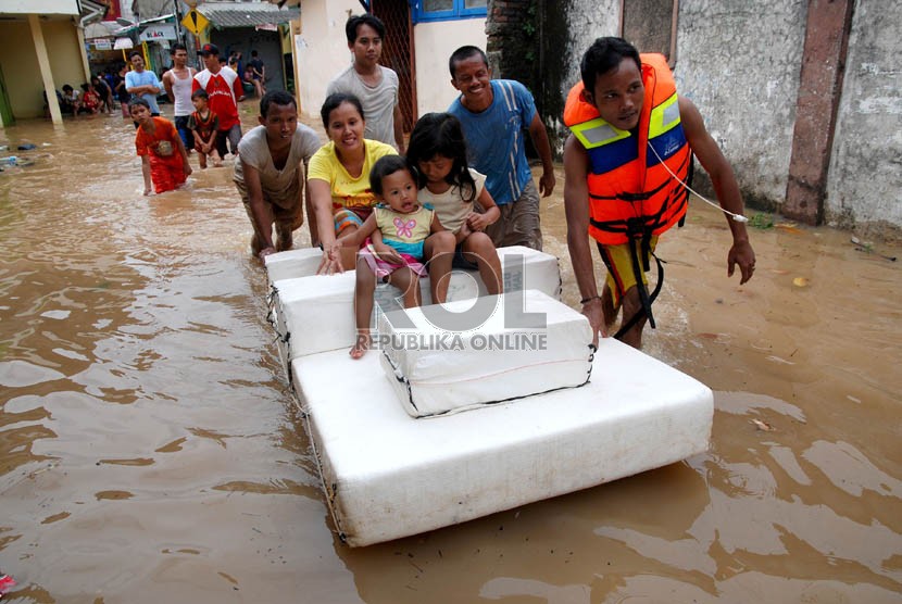   Warga menyelamatkan keluarga mereka saat banjir merendam rumah mereka di Kampung Poncol,Kelurahan Bukit Duri, Kecamatan Tebet,Jakarta Selatan,Senin (24/12).  (Republika/Prayogi)