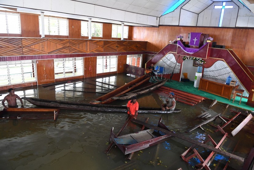 Warga merapikan kursi gereja yang terendam banjir akibat meluapnya Danau Sentani dampak dari banjir bandang Sentani di Kampung Yoboi, Danau Sentani, Sentani, Jaya Pura, Papua, Jumat (22/3/2019).