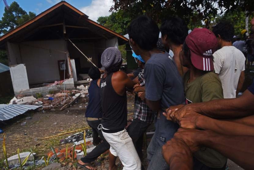 Warga merobohkan rumah yang rusak akibat gempa bumi di Kayangan, Lombok Utara, NTB, Minggu (12/8).