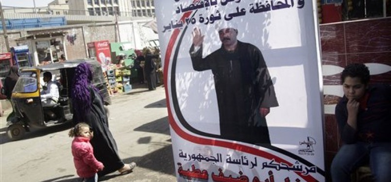 Warga Mesir berjalan melewati sebuah banner kampanye salah satu kandidat Presiden Mesir, Farghal Abou Daif, di Ibukota Kairo, Rabu (14/3). (ilustrasi)