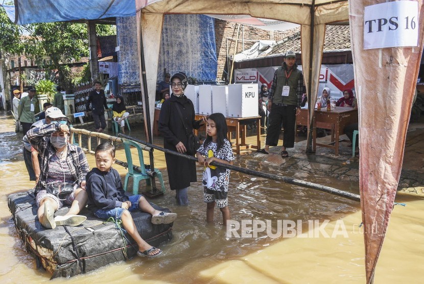 Warga mnggunakan rakit melintas di depan TPS. KPU DKI Jakarta sebut sebanyak 2.841 TPS ada di daerah rawan banjir.