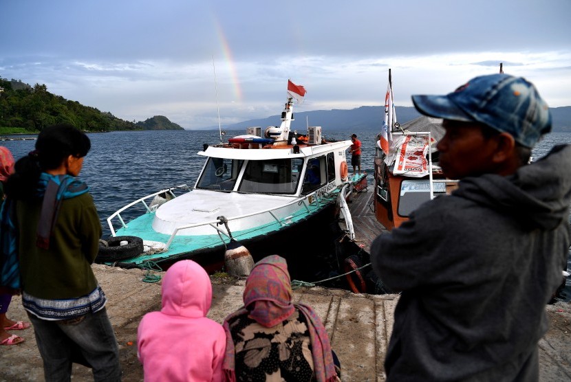Warga mnyaksikan kapal Basarnas berlabuh usai operasi SAR korban tenggelamnya KM Sinar Bangun di dermaga Tigaras, Danau Toba, Simalungun, Sumatera Utara, Minggu (1/7). 