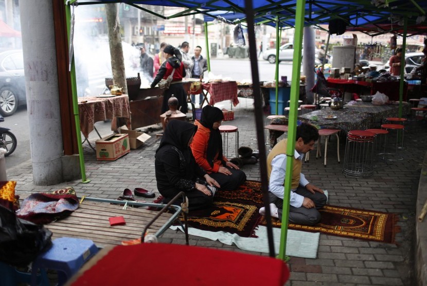 Warga Muslim Uighur Cina menunaikan ibadah di tengah aktivitas siang hari.