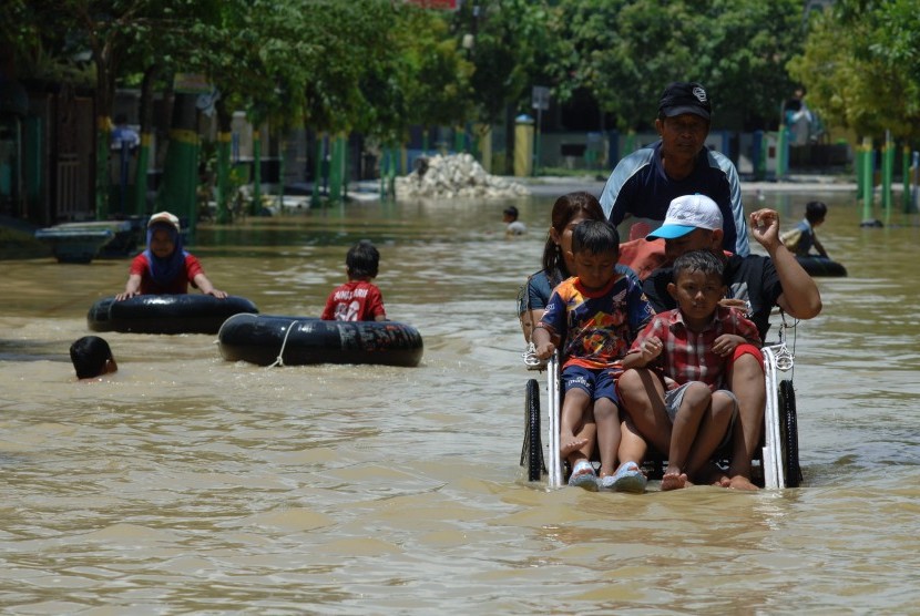 Warga naik becak menerobos banjir di Jalan Imam, Sampang, Jatim.