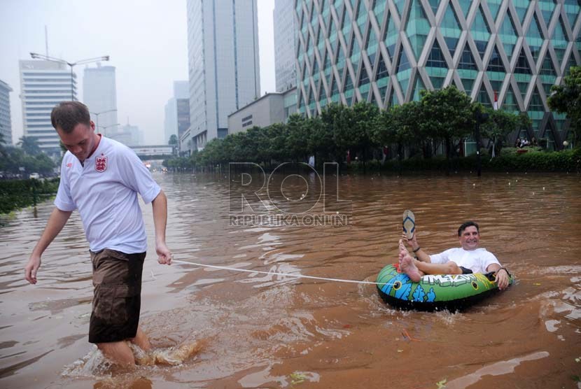  Warga negara asing asal Inggris Tim Lehman (kiri) menarik perahu karet yang ditumpangi warga Swiss Tom Hausler (kanan) saat banjir melanda di Jalan MH Thamrin, Jakarta, Kamis (17/1).  (Republika/Aditya Pradana Putra)