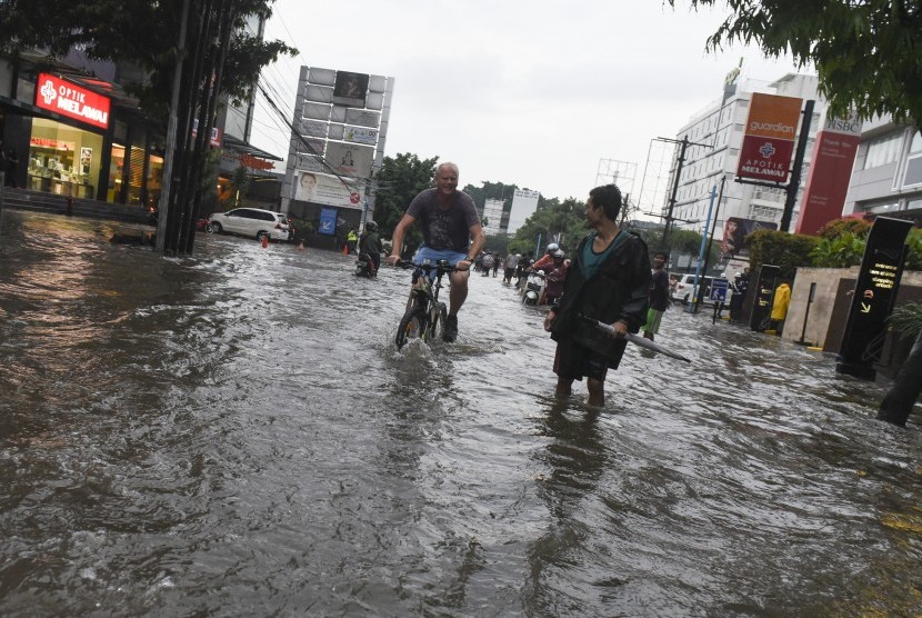 Warga negara asing menggunakan sepeda saat melintasi banjir di kawasan Kemang, Jakarta, Jumat (11/11). 