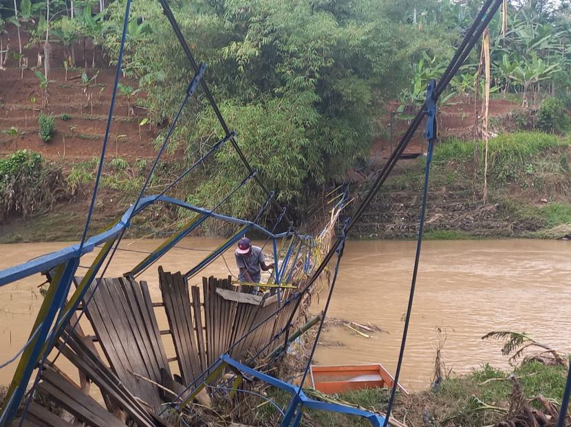 Warga nekat melintasi jembatan gantung rusak untuk menyeberang Sungai Ciseel di Dusun Gunungsari, Desa Ciparay, Kecamatan Cidolog, Kabupaten Ciamis, Kamis (10/11/2022). Rusaknya jembatan itu mengakibatkan ratusan warga di wilayah tersebut terisolasi.