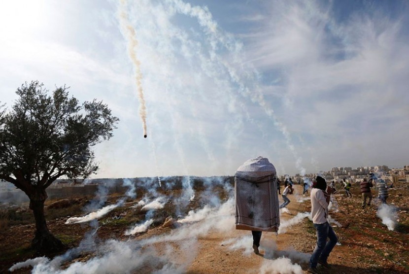 Warga Palestina berhamburan setelah ditembak gas air mata oleh tentara Israel