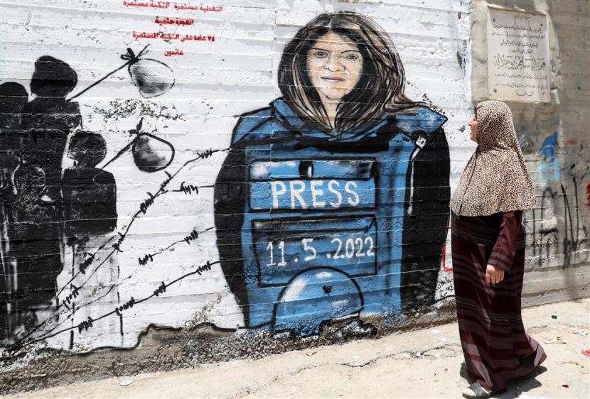 Warga Palestina berjalan di depan mural untuk jurnalis Al Jazeera Shireen Abu Akleh di kota Bethlehem di Tepi Barat, 16 Mei 2022. Wartawan Al Jazeera Shireen Abu Akleh dibunuh pada 11 Mei 2022 saat penggerebekan oleh pasukan Israel di kota Tepi Barat Jenin. 