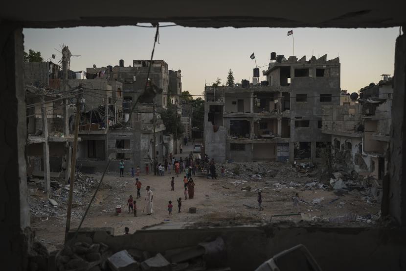  Warga Palestina berjalan di sepanjang Jalan Al-Baali di samping puing-puing rumah yang rusak parah akibat serangan udara selama perang 11 hari antara Israel dan Hamas, kelompok militan yang menguasai Gaza, di Beit Hanoun, Jalur Gaza utara, Rabu, 16 Juni 2021. Sejak 2008, lebih dari 4.000 warga Palestina tewas dalam empat perang, menurut PBB.