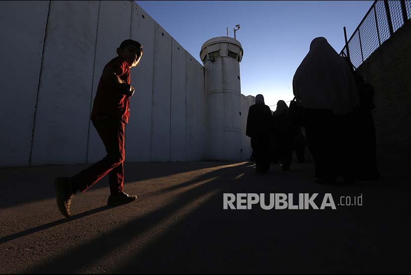 Warga Palestina berjalan melaui tembok pemisah di pos pemeriksaan menuju kawasan kompleks Al Quds di Jerusalem, Jumat (16/6). Israel melakukan pengawasan ketat termasuk menentukan siapa yang boleh memasuki komples masjid Al Aqsa tersebut.