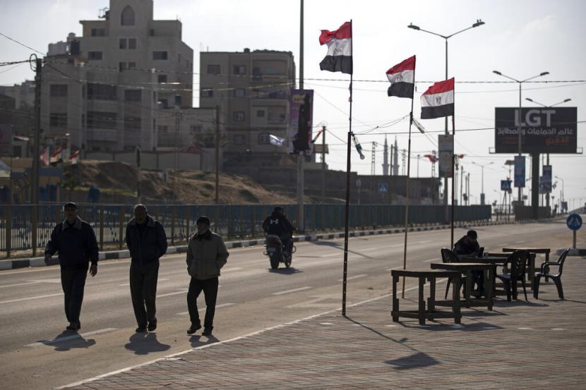Warga Palestina berjalan melewati bendera Mesir di sisi jalan di Beit Lahiya, di utara Jalur Gaza, 25 Januari 2022. Setelah bertahun-tahun bekerja di belakang layar, Mesir kini mengambil peran lebih besar di Gaza.