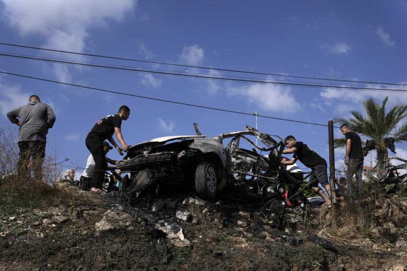 Warga Palestina berkumpul di sekitar mobil yang hancur akibat serangan pesawat nirawak di desa Zeita, sebelah utara kota Tulkarem, Tepi Barat, Sabtu, 3 Agustus 2024. Militer Israel mengatakan telah menyerang lima tersangka teroris di dalam kendaraan yang mereka tumpangi untuk melakukan serangan.