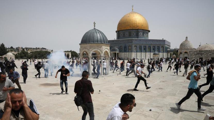Warga Palestina berlarian ketika ada bom suara yang dilemparkan oleh polisi Israel di depan kuil Dome of the Rock di kompleks Masjid Al Aqsa di Yerusalem yang diduduki, pada 21 Mei 2021. 