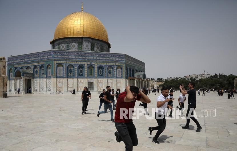 Warga Palestina lari dari bom suara yang dilemparkan oleh polisi Israel di depan kuil Dome of the Rock di kompleks masjid al-Aqsa di Yerusalem, Jumat (21/5), ketika gencatan senjata mulai berlaku antara Hamas dan Israel setelah perang 11 hari. .