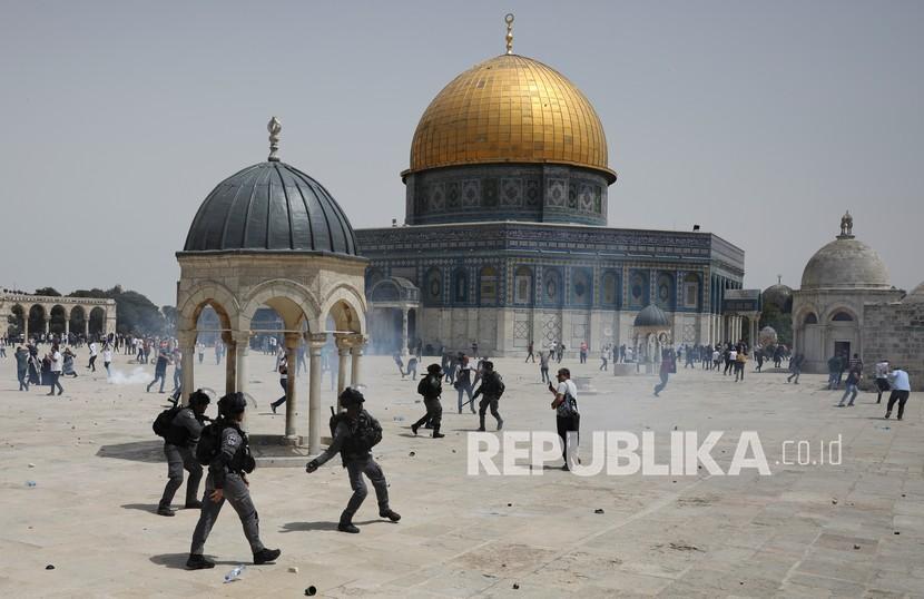 Warga Palestina lari dari bom suara yang dilemparkan oleh polisi Israel di depan kuil Dome of the Rock di kompleks Masjid al-Aqsha al-Aqsa di Yerusalem, Jumat (21/5), ketika gencatan senjata mulai berlaku antara Hamas dan Israel setelah perang 11 hari.