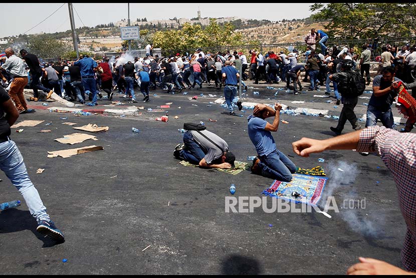 Warga Palestina melaksanakan Shalat Jumat berlarian saat kanister gas air mata yang ditembakkan polisi Israel meledak. Sebelumnya mereka melaksanakan shalat jumat  di jalan menuju di Kota Tua Yerusalem tersebut, Jumat (21/7).