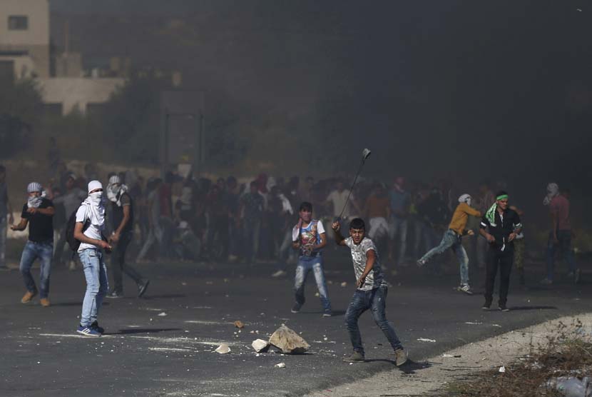 Warga Palestina melakukan aksi protes dalam bentrokan dengan tentara Israel di Hawara, Tepi Barat, Palestina, Ahad (11/10).