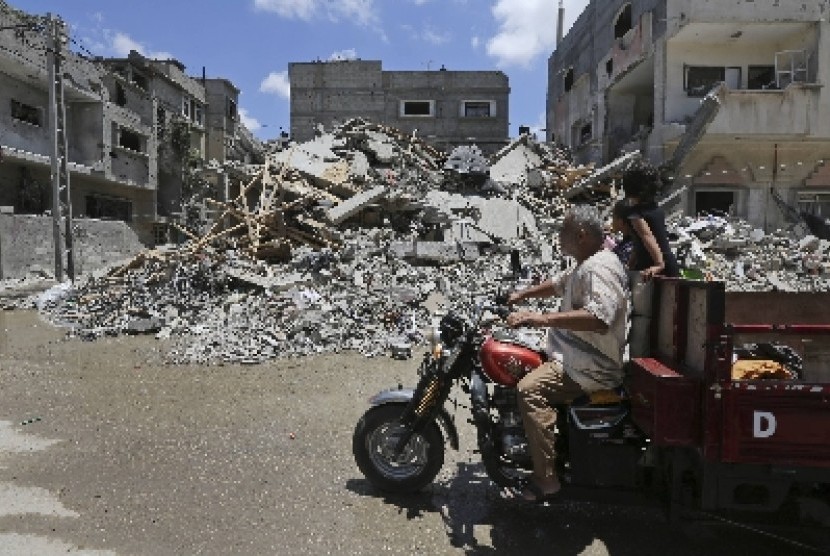 Warga Palestina melewati reruntuhan rumah yang hancur akibat serangan rudal Israel di Rafah, Gaza selatan, Palestina.
