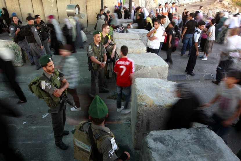 Warga Palestina melewati sebuah pos pemeriksaan tentara Israel dalam perjalanan mereka untuk Shalat Jumat di Masjid Al-Aqsa, Yerusalem, Jumat (10/8). (Majdi Muhammad/AP)