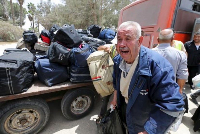 Warga Palestina membawa barang untuk melintasi perlinatasan Rafah.