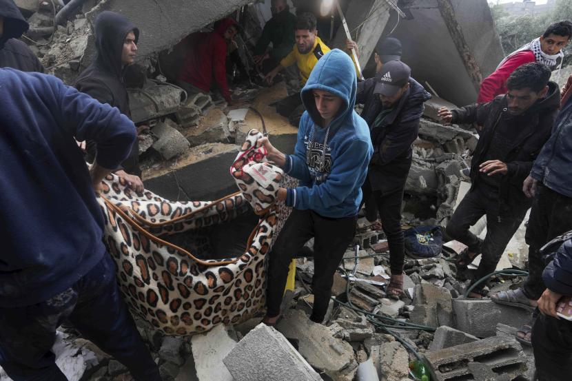 Warga Palestina membawa jenazah keluar dari puing-puing bangunan keluarga Al Nawasrah yang hancur akibat serangan udara Israel di kamp pengungsi Maghazi, Jalur Gaza tengah.