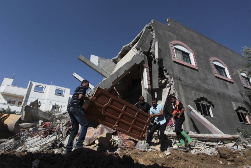 Warga Palestina membawa pintu dari rumah yang hancur akibat serangan udara Israel pada Rabu (9/7).  
