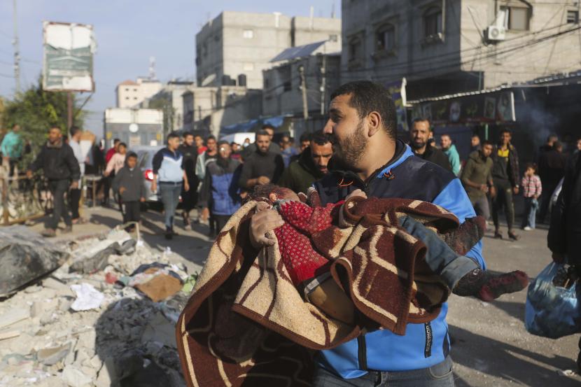 Warga Palestina membawa seorang anak yang tewas dalam pemboman Israel di Rafah, Jalur Gaza.