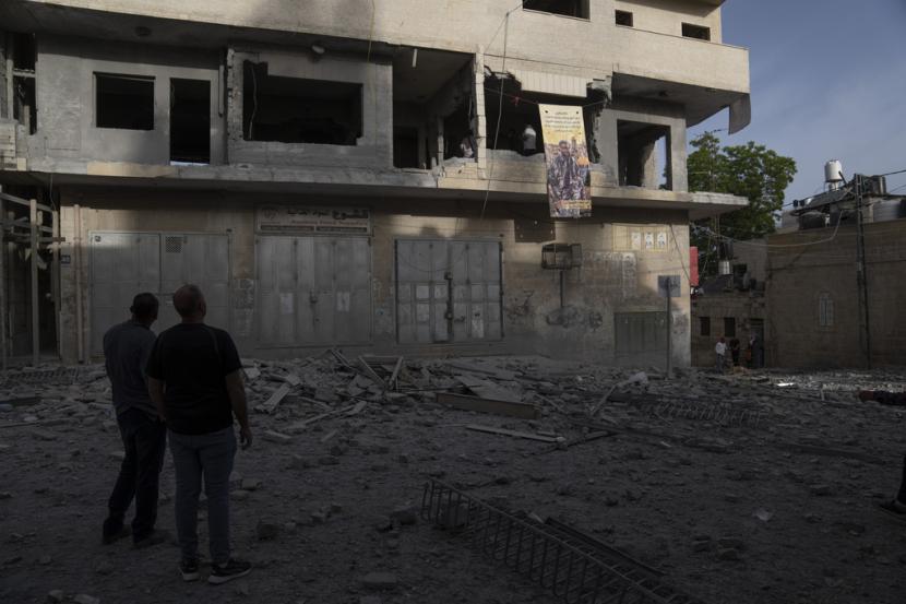 Warga Palestina memeriksa apartemen Islam Faroukh Palestina yang telah dihancurkan, terlihat pada poster yang tergantung di bagian depan gedung, di kota Ramallah, Tepi Barat, Kamis, 8 Juni 2023.