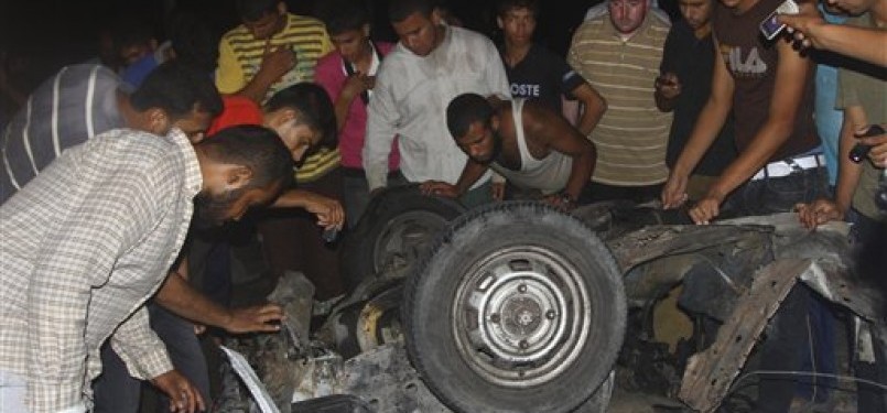 Warga Palestina memeriksa bangkai mobil yang dikendarai pejuang Jihad Islami, yang terkena serangan rudal Israel.