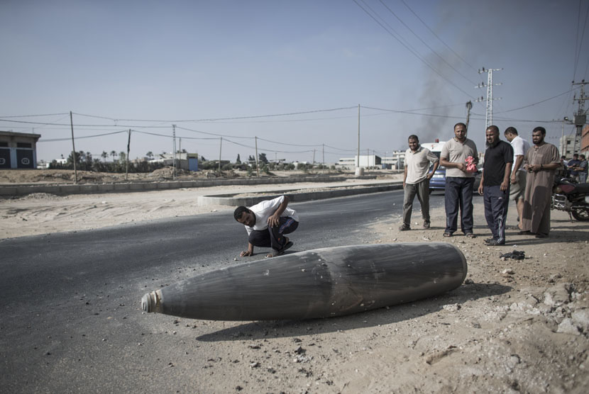  Warga Palestina mengamati bom Israel yang gagal meledak di Deir al-Balah, Gaza.