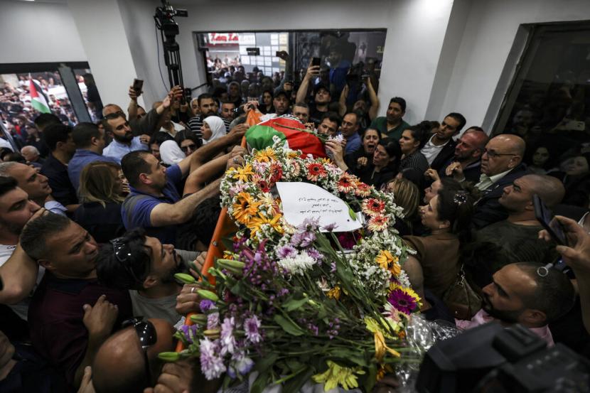 Warga Palestina mengepung jenazah jurnalis veteran Al-Jazeera Shireen Abu Akleh yang terbungkus bendera Palestina, saat dibawa ke kantor saluran berita di kota Ramallah, Tepi Barat, Rabu, 11 Mei 2022. 