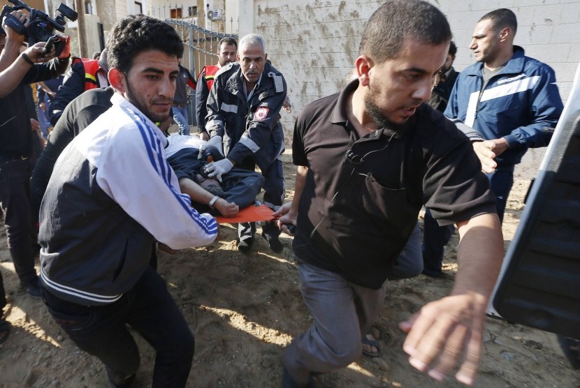 Warga Palestina mengevakuasi seorang pria yang terluka setelah Israel melakukan serangan udara di Jalur Gaza pada Kamis (15/11). Jumlah korban di pihak Palestina mencapai 13 orang dan tiga orang dari pihak Israel, sehingga ancaman serangan habis-habisan ol