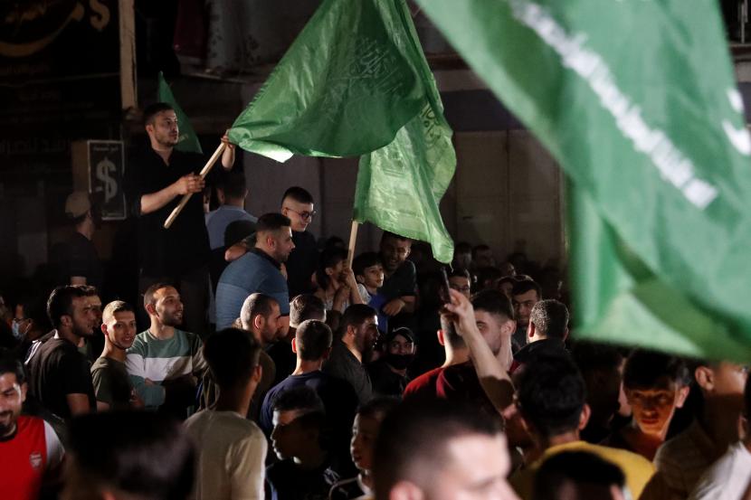 Warga Palestina mengibarkan bendera hijau Hamas saat merayakan kesepakatan gencatan senjata antara Israel dan Hamas di Kota Gaza, Jumat dini hari, 21 Mei 2021.