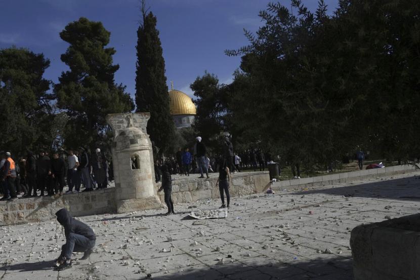 Penggalian Israel Bisa Sebabkan Runtuhnya Masjid Al Aqsa. Foto:   Warga Palestina mengumpulkan batu untuk dilemparkan ke polisi Israel setelah mereka memasuki kompleks Masjid Al Aqsa, di Kota Tua Yerusalem, Jumat, 22 April 2022.