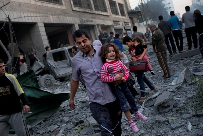 Warga Palestina meninggalkan rumah mereka yang hancur diserang Israel, di dekat lapangan Kota Gaza, Senin (19/11).